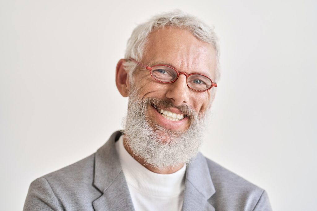 Happy older business man wearing glasses isolated on white, headshot portrait.